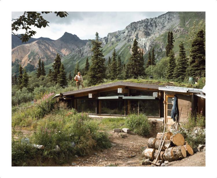Joel Sternfeld, A Woman at Home in Palmer, Alaska. The Church Mountains are seen in the Bachgro…