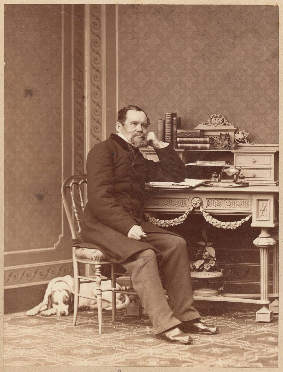 Fritz Luckhardt, Bildnis Heinrich Laube, ganze Figur, an einem Schreibtisch sitzend, einen Hund…